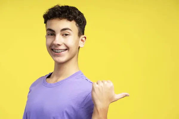 Kjekk Smilende Gutt Tenåring Med Tannregulering Pekende Med Fingeren Kopieringsplass – stockfoto