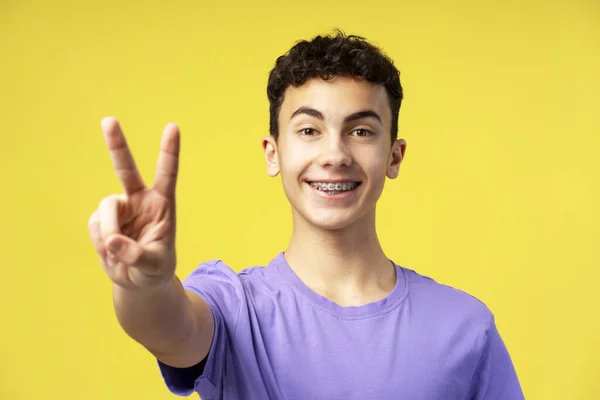 행복한 매력적인 소년의 초상화 노란색 배경에 카메라를 손가락으로 기호를 보여주는 — 스톡 사진