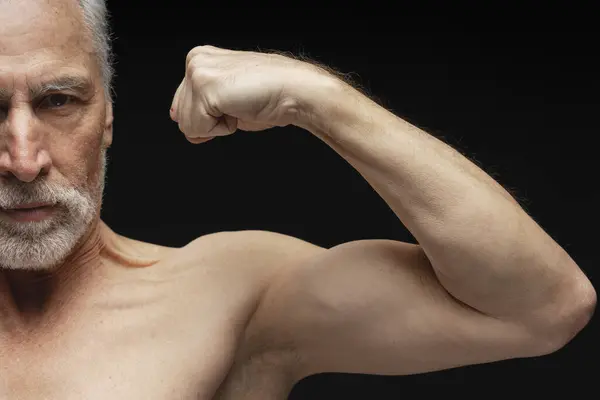 严肃的已退休的成熟男子的画像 赤身裸体的运动员表现出二头肌 肌肉发达的身体被黑色背景隔离 概念广告 健康的生活方式 — 图库照片