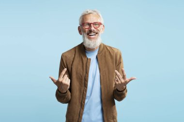 Gülümseyen yakışıklı sakallı iş adamı, menajer, kırmızı gözlük takan şık CEO mavi arka planda izole edilmiş bir video konuşmasını açıklıyor. Başarılı iş konsepti 