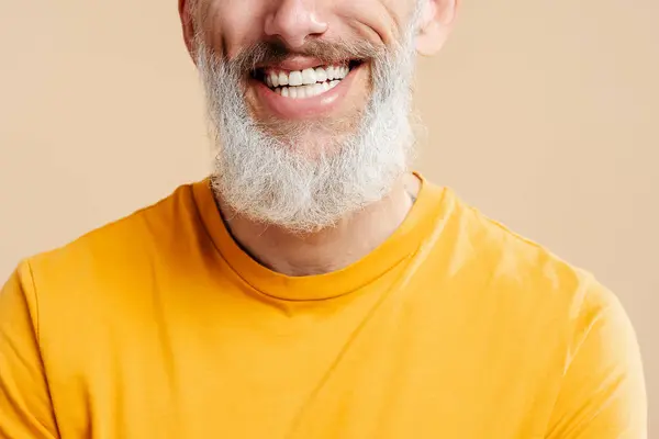 服装肖像英俊的笑容50岁的男子与时尚的灰色胡子 白色的牙齿穿着休闲橙色T恤 看着相机孤立的背景 牙科治疗概念 — 图库照片