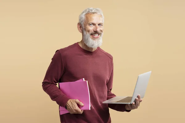 英俊的白发苍苍的生意人 留着胡子的嬉皮士拿着手提电脑 看着被背景隔离的相机 快乐的现代成熟程序员的肖像 成功的业务 — 图库照片