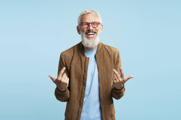 Портрет улыбающийся красивый бородатый бизнесмен, менеджер, стильный генеральный директор в красных очках, объясняющий что-то с видеозвонком, изолированный на синем фоне. Успешная бизнес-концепция 