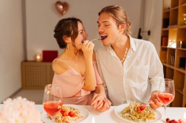 Mutlu, gülümseyen genç adam ve kadının portresi. Yemek yiyor, restoranda oturuyor. Çekici romantik çift doğum gününü kutluyor. Aşk kavramı, flört.