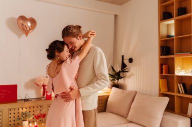 Çekici genç bir çiftin portresi. Evde dikilirken birbirlerine sarılıyorlar. Romantik bir flört. Aşk kavramı, ilişkiler