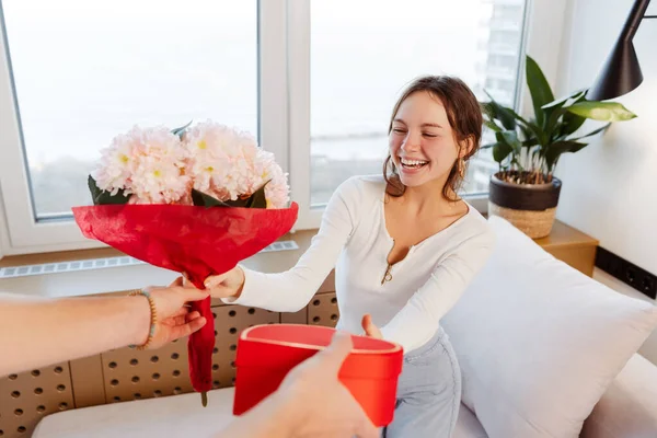 笑顔の若い女性に美しい花とギフトボックスの花束を贈る男 自宅で幸せなロマンチックなカップルの誕生日を祝う肖像画 デート バレンタインデーのコンセプト — ストック写真