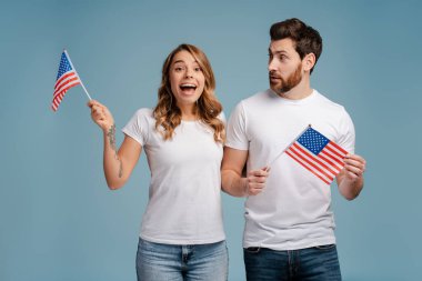 Gülümseyen çekici bir çiftin portresi, ellerinde Amerikan bayraklarıyla televizyon seyreden taraftarlar, mavi arka planda seçim sonuçlarını bekliyorlar. Seçim günü, seçim konsepti