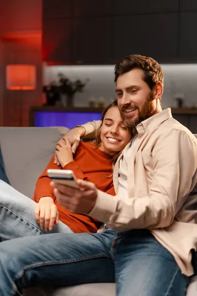 Älskade Leende Par Som Håller Smartphone Titta Video Sitter Soffan — Stockfoto