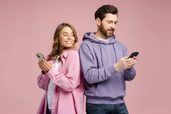 Gülümseyen Kadın Pembe Arka Planda Sakallı Erkek Arkadaşının Akıllı Telefonuna — Stok fotoğraf