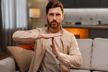 Çekici, ciddi sakallı bir adamın portresi, çevirmen işaret diliyle konuşuyor, el kol hareketi yapıyor, evdeki kanepede otururken kameraya bakıyor. İletişim konseptiyle ilgili sorunlar