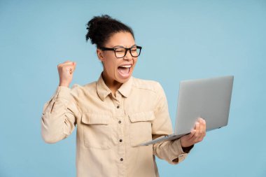 Çekici gülümseyen kadın portresi, para kazanmak, dizüstü bilgisayar kullanmak, video izlemek, online alışveriş yapmak mavi arka planda izole edilmiş. Spor bahisleri, teknoloji konsepti