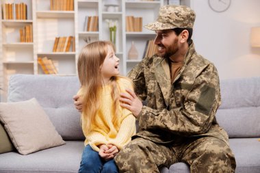 Ukrayna ordusundaki baba, kızını şaşırtıyor, ona kanepede katılıyor, mutlu bir şekilde bir araya geliyorlar.