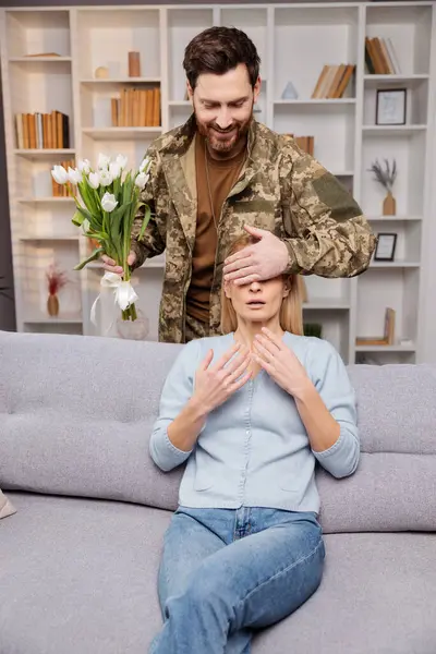 乌克兰士兵下班回来 用鲜花给他的伴侣带来惊喜 他轻轻捂住她的眼睛 等待她认出他来 她的心因期待而怦怦直跳 温馨温馨的家庭氛围 — 图库照片