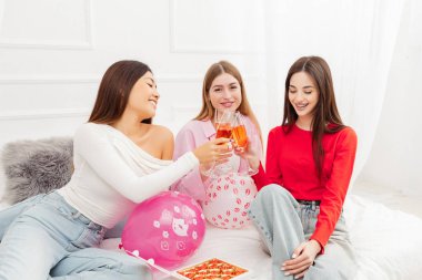 Bir grup gülümseyen güzel kadın şarap içiyor, çikolata yiyor, bekarlığa veda partisinde kanepede oturuyor. Doğum günü kavramı