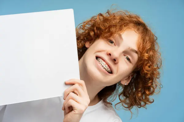 Curly Smiling Ginger Boy Braces Holding Blank White Poster Isolated — Stock Photo, Image