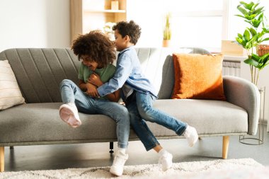 Pozitif, güzel Afro-Amerikan kardeşler evdeki rahat kanepede birlikte takılıyorlar. Çocukluk kavramı, aile, eğlence