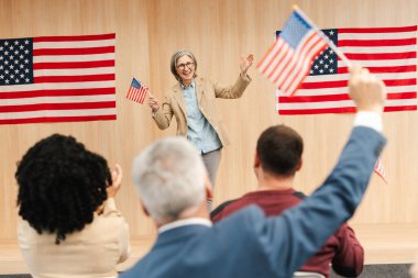 Portrait of smiling confident woman, politician, presidential candidate holding American flag communication, speaking with audience. Vote, United States presidential election concept  clipart