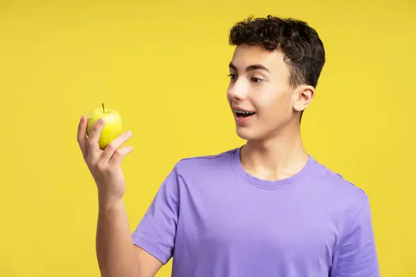 Emocionado Adolescente Guapo Sosteniendo Manzana Fruta Mirándolo Pie Aislado Sobre — Foto de Stock