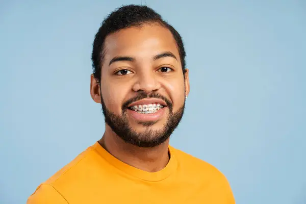 一个身穿休闲装的非洲裔美国学生的肖像照片 直接看着相机 面带微笑地摆姿势 与蓝色的画室背景隔离 — 图库照片
