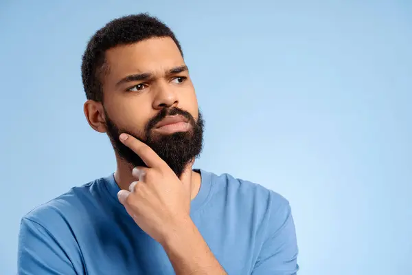 stock image Serious, pensive, authentic African American man with beard looking away, copy space isolated on blue background. Advertisement concept