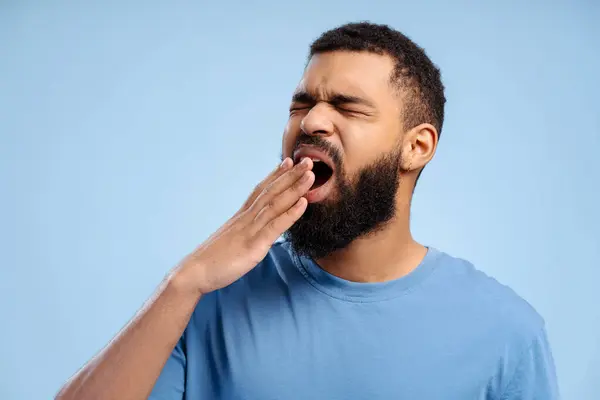 Уставший Бородатый Афроамериканец Зевает Скучает Закрытыми Глазами Позирует Изолированным Синем — стоковое фото