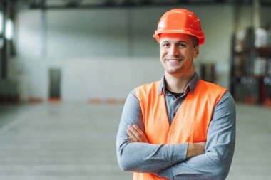 Yakışıklı, adam, ustabaşı, iş kıyafeti ve şapka takan, çapraz kollu kameraya bakan, depoda fotokopi çeken. Endüstri kavramı, reklam