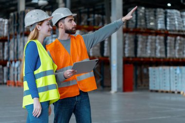 Çekici işçiler, mühendisler, koruyucu iş kıyafetleri ve güvenlik kaskları takan, dijital tablet kullanan, el işaretli fabrika ustabaşı, kopyalama alanı, depoda duran. Lojistik, takım çalışması konsepti
