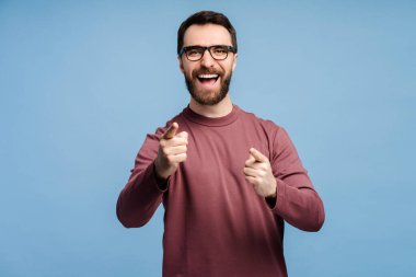 Gözlüklü, gözlüklü yakışıklı bir adamın portresi. Mavi arka planda izole bir şekilde kameraya bakıyor. Reklam kavramı