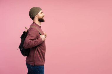 Sırt çantalı gülümseyen öğrencinin pembe arka planda izole bir şekilde bakışları. Eğitim konsepti. Mutlu ve çekici bir turistin portresi yolculuğa hazır.