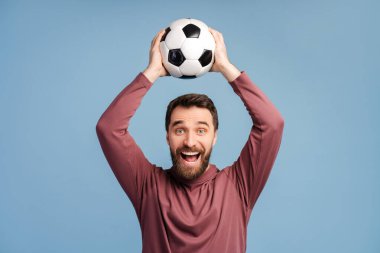 Çok mutlu bir adam, futbol fanatiği futbol topu tutuyor, seviniyor, arka planda izole edilmiş favori takımı destekliyor, maket yapıyor. Mutlu erkek futbol maçı izliyor.