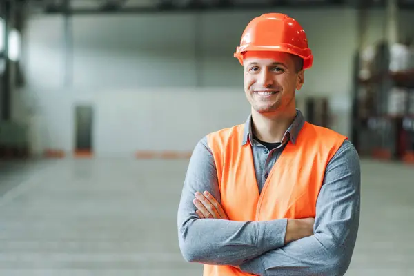 Yakışıklı, adam, ustabaşı, iş kıyafeti ve şapka takan, çapraz kollu kameraya bakan, depoda fotokopi çeken. Endüstri kavramı, reklam