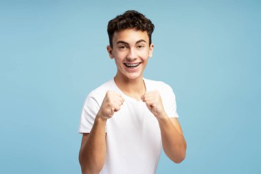 Çekici, heyecanlı, genç, yumrukları olan, kavga eden, mücadele eden, kameraya bakan, mavi arka planda izole edilmiş. Spor anlayışı, rekabet