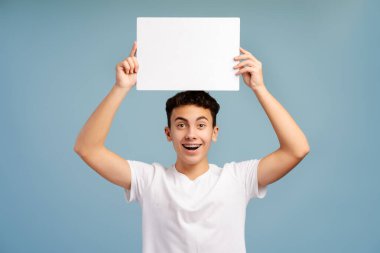 Heyecanlı, gülümseyen, diş telleri olan beyaz ekranlı bir çocuk mavi arka planda izole bir şekilde duran kameraya bakıyor. Reklam kavramı