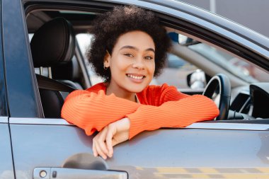 Güzel, otantik Afro-Amerikan kadın araba kullanıyor, kameraya bakıyor. Ulaşım kavramı, araç