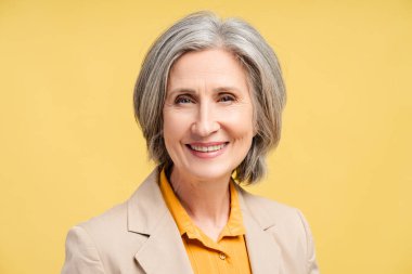 Portrait of happy senior gray haired woman, politician leader looking at camera isolated on yellow background. Successful business, career clipart