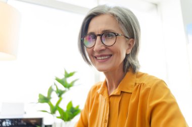 Gülümseyen grafik tasarımcı, editör, iş yerinde oturan rötuş uzmanı. Üst düzey bir kadın, modern ofiste çalışan mutlu bir serbest yazar. Teknoloji, başarılı iş konsepti