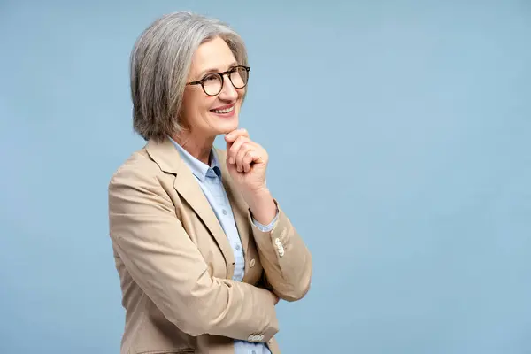 青い背景で孤立した考えを眼鏡をかけたシニアビジネス女性の笑顔 信頼できるグレーハイレッド政治家の肖像画 成功したビジネス キャリア ロイヤリティフリーのストック写真
