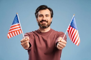 Mutlu sakallı adam mavi arka planda Amerika Birleşik Devletleri 'nin iki bayrağıyla kutlama yapıyor. Anma Günü Kutlaması, Bağımsızlık Günü.
