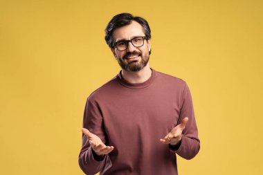 Stüdyoda, sarı arka planda izole edilmiş el ele tutuşurken kameraya bakan mutlu genç adamın portresi. Alışveriş, satış konsepti. Reklam.