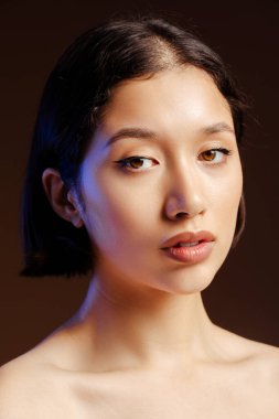 Koyu renk saçlı güzel bir kadının yakın plan güzel portresi, taze, sağlıklı bir ciltle kameraya bakıyor, izole edilmiş siyah arkaplanda çıplak poz veriyor.