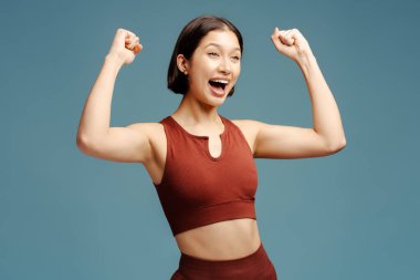 Heyecanlı esmer kadının portresi mavi arka planda izole bir şekilde sevinçten başka tarafa bakıyor. Zafer kavramı, rekabet