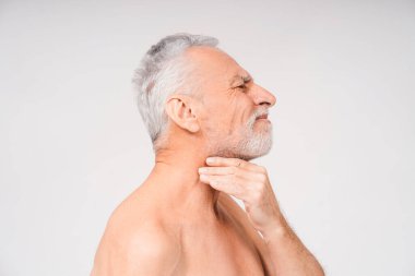 Beyaz arka planda boğaz ağrısından muzdarip, çıplak, gri saçlı, sakallı bir adamın yan görüntüsü. Soğuk belirtileri. Sağlık hizmeti kavramı