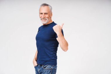 Mutlu, gri saçlı, şık kıyafetler giyen, beyaz üzerine izole edilmiş, fotokopi alanını gösteren, mutlu bir adamın portresi. Alışveriş, satış konsepti.