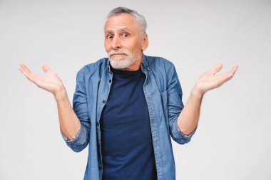 Yakışıklı, şaşkın, gri sakallı adamın portresi avuçlarını kaldırmış, hayretle kameraya bakıyor, beyaz arka planda poz veriyor.