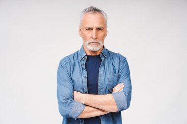 Stüdyoda kollarını kavuşturup beyaz arka planda izole edilmiş kameraya bakarak poz veren yaşlı gri saçlı mutlu bir adam. Halk yaşam tarzı konsepti