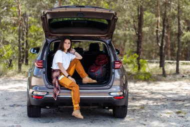 Güzel, genç bir kadın arabanın bagajında oturmuş, doğa yürüyüşüne çıkmaya hazırlanıyor. Macera konsepti