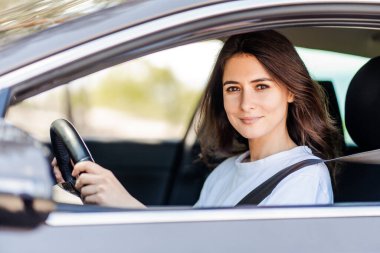 Mutlu kadın araba kullanıyor ve doğanın tadını çıkarırken gülümsüyor. Sevimli genç başarı mutlu esmer kadın araba kullanıyor. Emniyet kemeri takan mutlu kadın sürücü portresi.