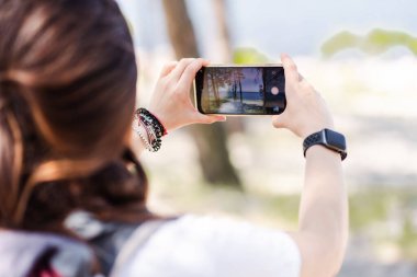 Dişi gezgin dağların resmini çekmek için akıllı telefon kullanır. Seyahat konsepti ve teknoloji. Doğanın resmini çeken bir turist. Sırt çantalı kadın fotoğrafçı fotoğraf çekiyor.