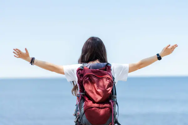 stock image Back view woman backpacker hiking in the river bank and enjoying freedom while travel on summer holiday vacation trip. Attractive girl traveler enjoy outdoor lifestyle walking by the lake