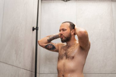 Baştan çıkarıcı yakışıklı genç sakallı adamın portresi duş alıyor, kulaklarını yıkıyor, banyoda poz veriyor. Çıplaklık, cinsellik kavramı